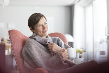 Portrait of smiling woman relaxing with cup of coffee at home - RBF05722