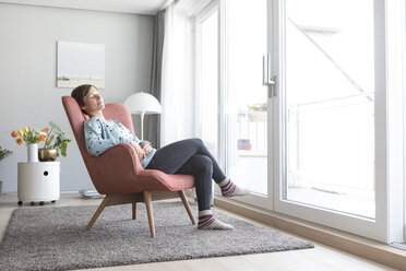 Frau entspannt sich auf einem Sessel zu Hause - RBF05725