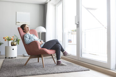 Woman relaxing on armchair at home - RBF05725