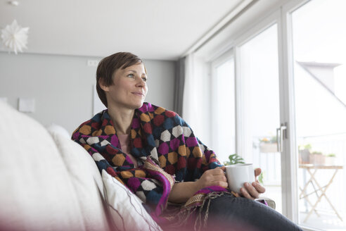 Porträt einer Frau, die sich mit einer Tasse Kaffee zu Hause entspannt - RBF05730