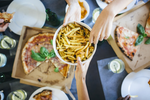 Hand nimmt Pommes frites aus Schüssel, lizenzfreies Stockfoto