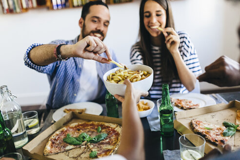 Glückliche Freunde bei Pommes frites und Pizza zu Hause - GIOF02752