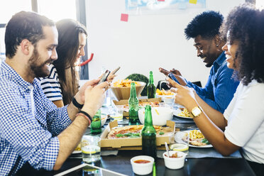 Friends using cell phones at dining table - GIOF02758