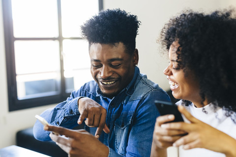Glückliches Paar schaut auf Handy, lizenzfreies Stockfoto