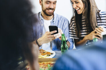 Glückliches Paar teilt Handy am Esstisch - GIOF02764