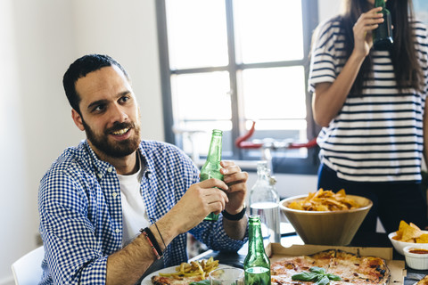 Mann und Frau mit Bierflaschen am Esstisch, lizenzfreies Stockfoto