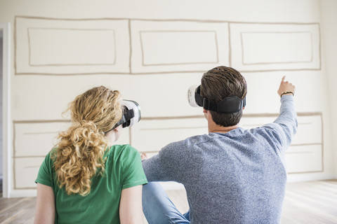 Young couple in new home wearing VR glasses thinking about interior design stock photo
