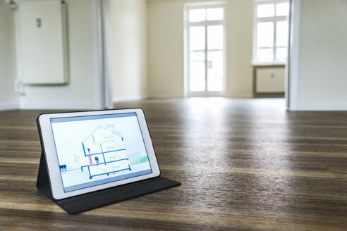 Tablet mit Hausmodell auf Holzboden - UUF10830