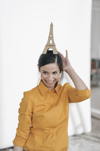 Junge Frau mit Modell des Eiffelturms, die eine Reise nach Paris plant, lizenzfreies Stockfoto