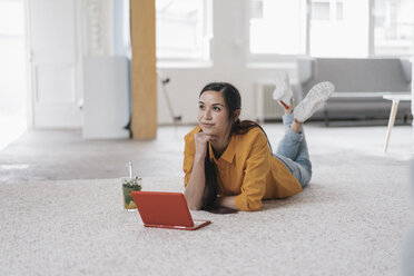 Junge Frau mit Laptop, auf dem Boden liegend, nachdenklich - JOSF01103