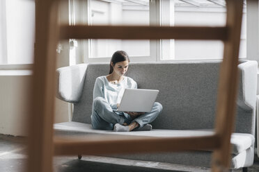 Junge Frau sitzt in ihrer neuen Wohnung mit einem Laptop - JOSF01106