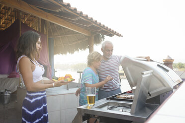 Family barbecue with older man, young woman and girl on a penthouse terrace - ABAF02159