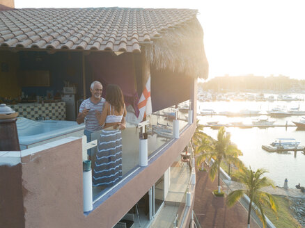 Unequal couple - older man and young woman enjoying evening on penthouse terrace, Nuevo Vallarta, Nayarit, Mexico - ABAF02162