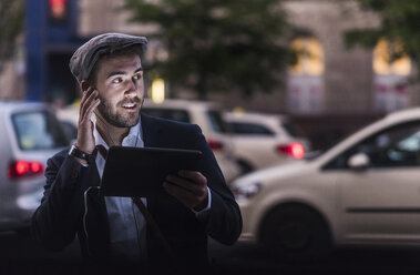 Junger Mann in der Stadt mit Kopfhörern und Tablet - UUF10857