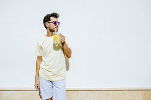 Mann mit Sonnenbrille und Limonade vor weißer Wand - KIJF01518