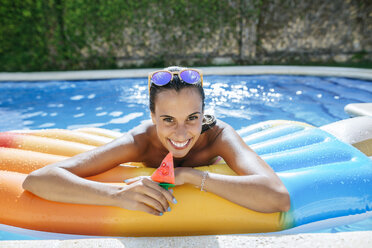 Portrait of happy young woman on airbed in swimming pool - KIJF01535