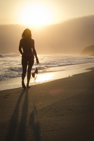 Mexico, Riviera Nayarit, silhouette of woman walking into the sunset at a beach while holding her bikini top stock photo