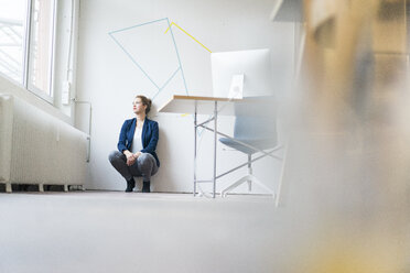 Business woman crouching on floor, looking out of window, thinking - JOSF01134