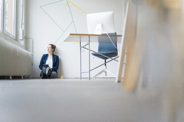 Business woman sitting on floor, looking out of window, thinking - JOSF01135
