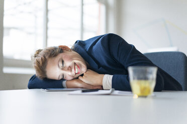 Businesswoman lying over desk, chatting on digital tablet - JOSF01142