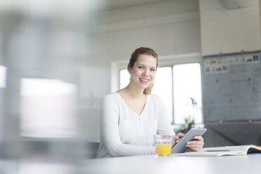 Businesswoman working at desk in her office, using digital tablet - JOSF01154