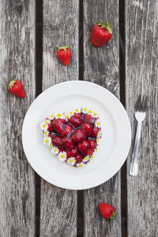 Hausgemachtes Erdbeertörtchen in Herzform mit Gänseblümchen verziert, lizenzfreies Stockfoto