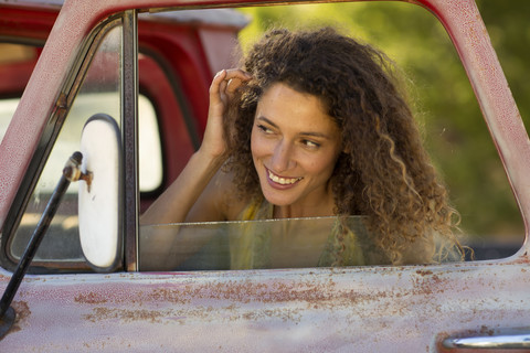 Glückliche junge Frau, die ihr Haar im Autospiegel fixiert, lizenzfreies Stockfoto