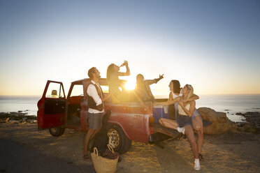 Glückliche junge Leute vor einem Pick-up-Truck an der Küste bei Sonnenuntergang - ZEF13916