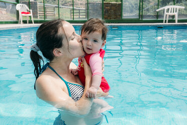 Mother kissing her baby girl in swimming pool - GEMF01677
