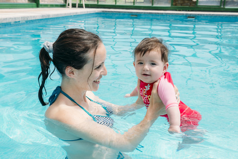 Niedliches kleines Mädchen, das mit seiner Mutter im Pool schwimmen lernt, lizenzfreies Stockfoto