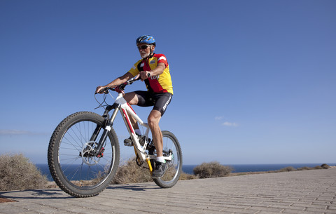 Spanien, Kanarische Inseln, Fuerteventura, älterer Mann auf Mountainbike, lizenzfreies Stockfoto