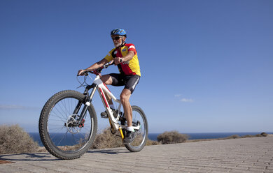 Spanien, Kanarische Inseln, Fuerteventura, älterer Mann auf Mountainbike - MFRF00842