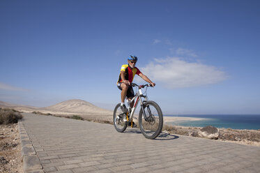 Spanien, Kanarische Inseln, Fuerteventura, älterer Mann auf Mountainbike - MFRF00843