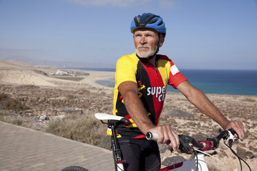 Spanien, Kanarische Inseln, Fuerteventura, älterer Mann mit Mountainbike beim Ausruhen - MFRF00846
