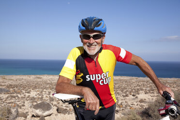 Spanien, Kanarische Inseln, Fuerteventura, lächelnder älterer Mann mit Mountainbike - MFRF00847