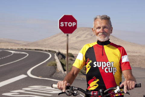 Spanien, Kanarische Inseln, Fuerteventura, Porträt eines selbstbewussten älteren Mannes mit Mountainbike, lizenzfreies Stockfoto
