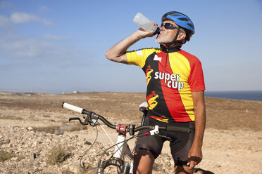 Spanien, Kanarische Inseln, Fuerteventura, älterer Mann mit Mountainbike trinkt aus Flasche - MFRF00853