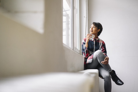 Woman sitting at the window holding cup stock photo