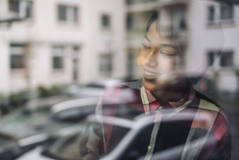 Smiling young woman behind windowpane - KNSF01525