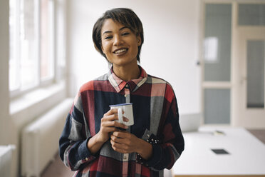 Portrait of smiling young woman holding cup - KNSF01526