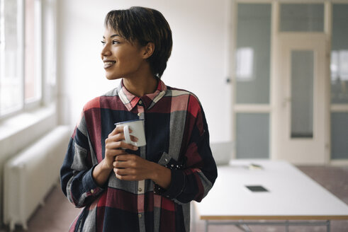 Smiling young woman holding cup - KNSF01527