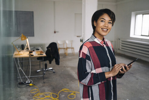 Smiling woman using tablet in empty office - KNSF01534