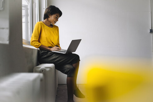 Woman sitting at the window using laptop - KNSF01538