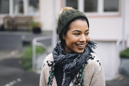 Smiling young woman wearing wooly hat outdoors - KNSF01541