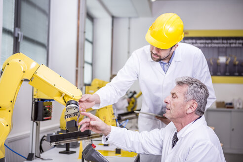 Two engineers examining industrial robot - WESTF23397