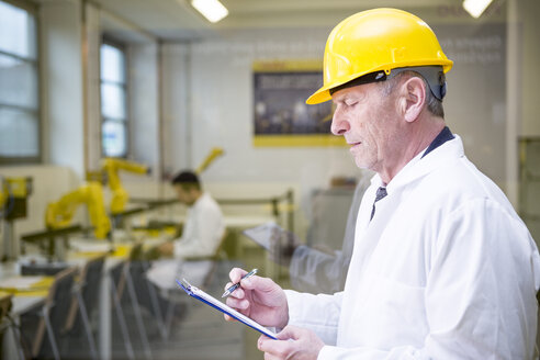 Engineer in factory with clipboard - WESTF23399