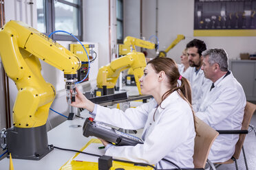 Engineers examining industrial robots - WESTF23406