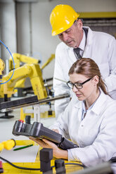 Two engineers in factory looking at device - WESTF23409