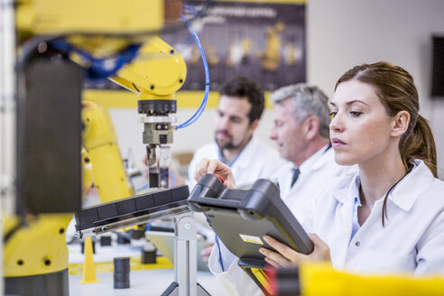 Engineers examining industrial robots - WESTF23411