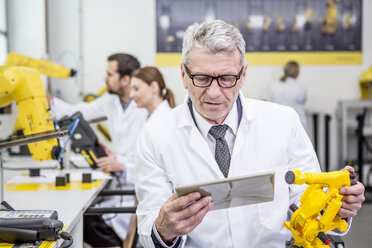 Engineer holding tablet and model of an industrial robot - WESTF23417